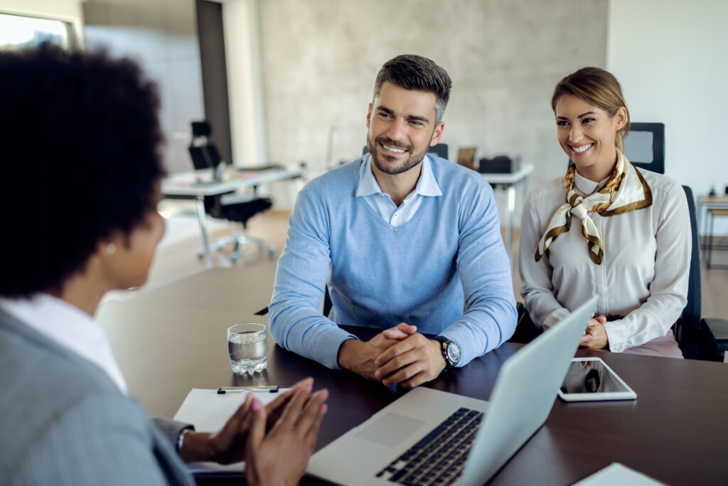 young happy couple having meeting with real estate agent office